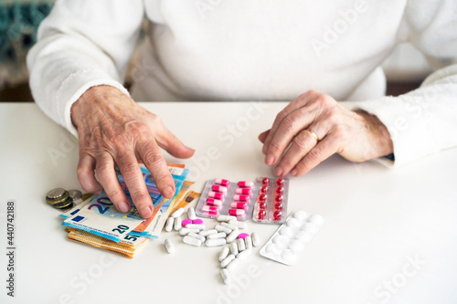An older retired woman is counting money and saving it for medicines, medical treatment and insurance. Taking care of your health and wise investment.