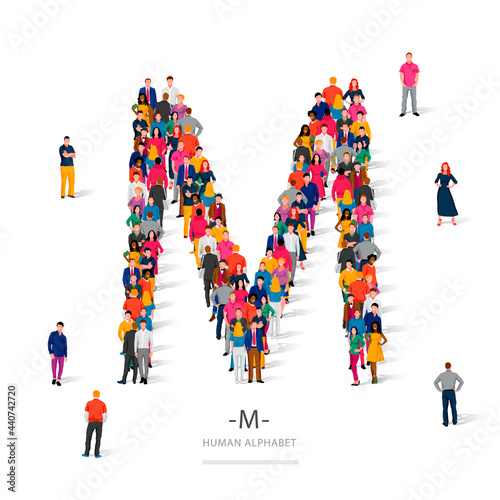 A large group of people is standing in colored clothes in the shape of the letter M. The concept of the human alphabet.