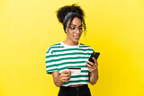 Young african american woman isolated on yellow background buying with the mobile with a credit card