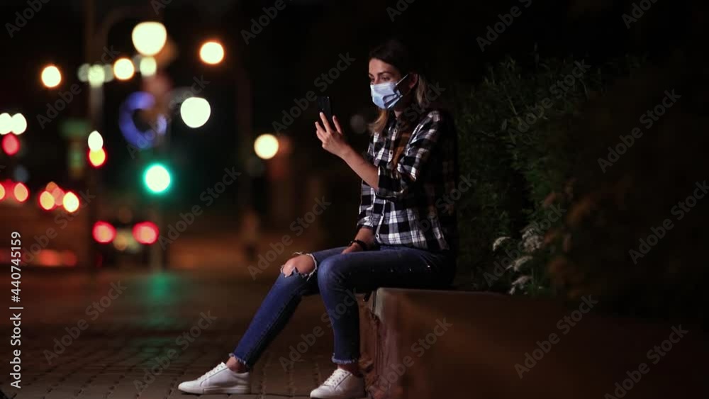 A white-skinned girl in a mask rejoices on the phone from the community. A young white-skinned girl in a protective mask at night in the city receives a pleasant message and is very happy. A white-skinned girl in a mask rejoices on the phone from the community. A young white-skinned girl in a protective mask at night in the city receives a pleasant message and is very happy.