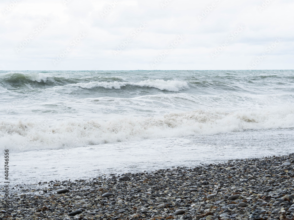 Storm waves on a stone beach in cloudy weather Storm waves on a stone beach in cloudy weather