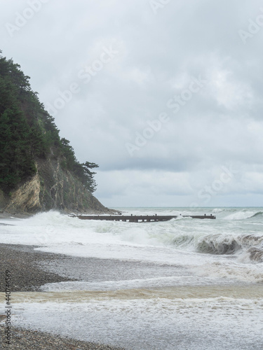 Storm waves on sea on stone beach in cloudy weather. Nature scenery
