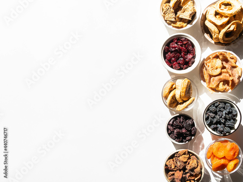 Flat lay various dried fruits and berries in bowls on white background with shadows. Vegan healthy natural snacks. © senteliaolga