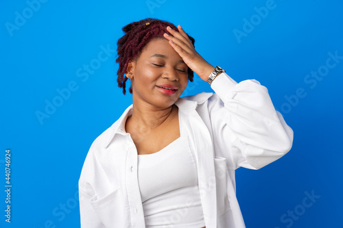 Young afro woman suffering headache against blue background