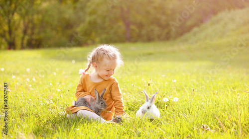 the girl sitting on the sunny lawn among the rabbits