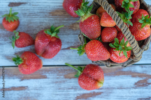 ripe fresh garden strawberries in a wicker vintage basket on a wooden background
