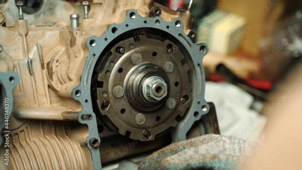 a man in work gloves installs a gasket between the engine and the gearbox a man in work gloves installs a gasket between the engine and the gearbox