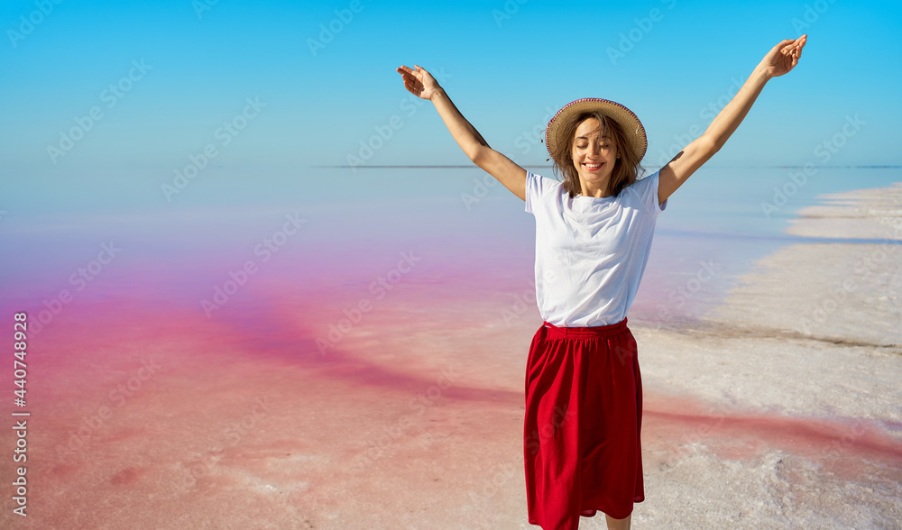 Tourist woman enjoying summer trip at pink lake, walking by salt flats with open arms Tourist woman enjoying summer trip at pink lake, walking by salt flats with open arms