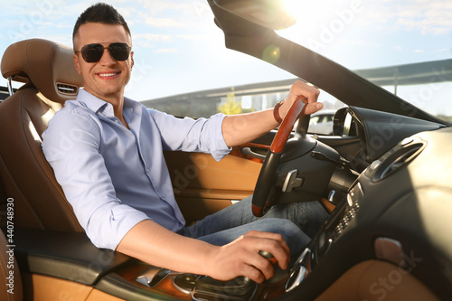 Businessman driving luxury convertible car outdoors on sunny day © New Africa