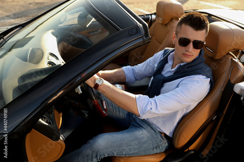 Handsome young man in luxury convertible car outdoors