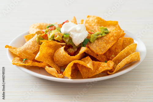 Fotografie nachos tortilla chips with jalapeno, guacamole, tomatoes salsa and dip