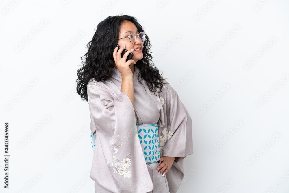 Young asian woman wearing kimono isolated on white background keeping a conversation with the mobile phone with someone Young asian woman wearing kimono isolated on white background keeping a conversation with the mobile phone with someone