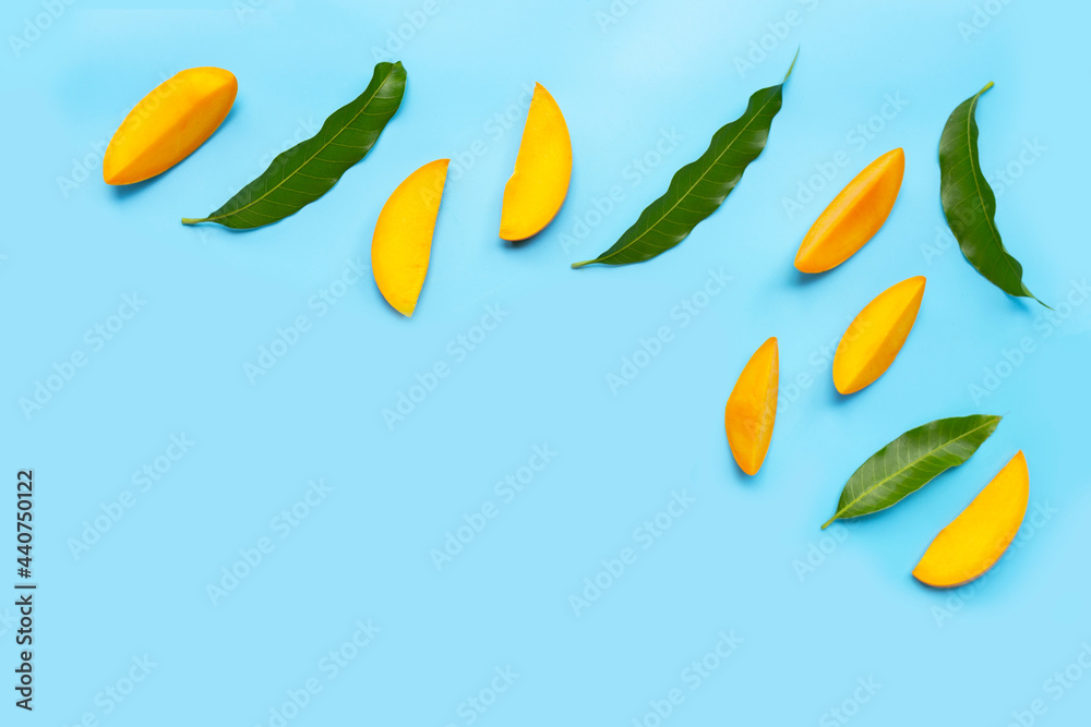 Fototapeta premium Tropical fruit, Mango slices with leaves on blue background.