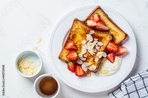 French toast with strawberries, yogurt and maple syrup on a white plate. Breakfast concept.