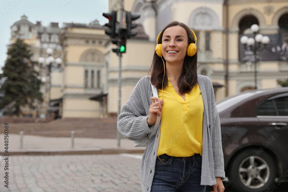 Young woman with headphones crossing street at traffic lights Young woman with headphones crossing street at traffic lights