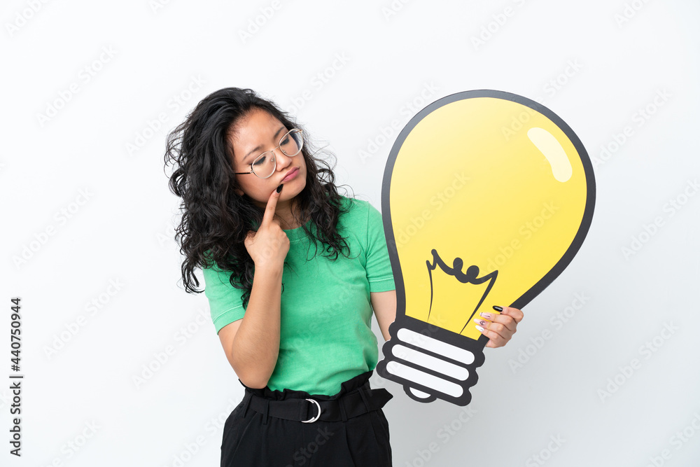 Young asian woman isolated on white background holding a bulb icon and having doubts Young asian woman isolated on white background holding a bulb icon and having doubts