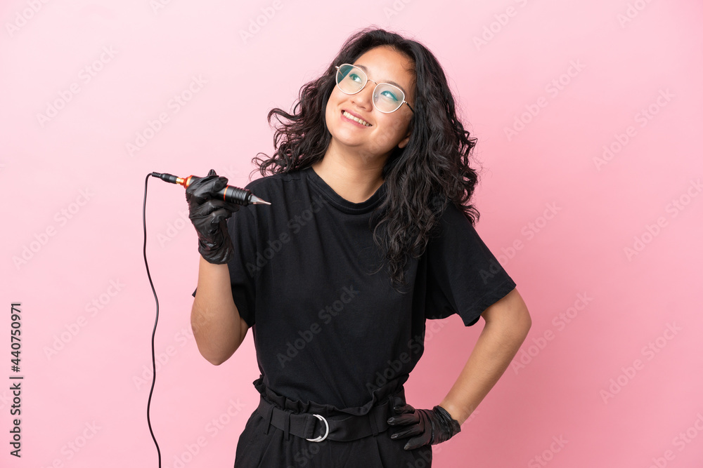 Tattoo artist asian woman isolated on pink background thinking an idea while looking up