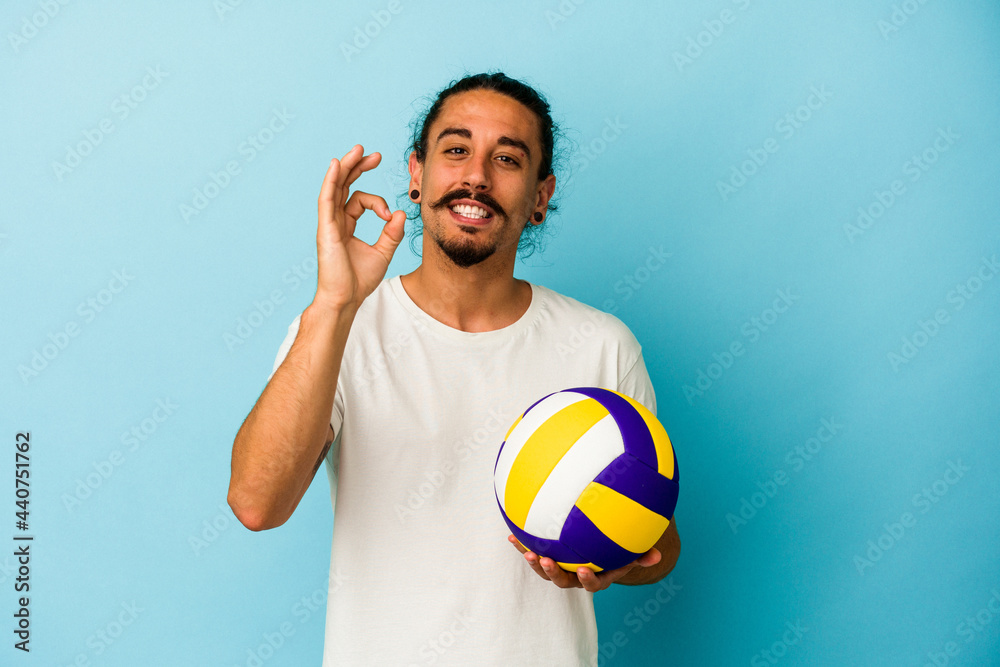 Young caucasian man with long hair isolated on blue background cheerful and confident showing ok gesture.