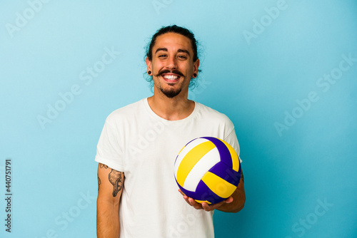 Young caucasian man with long hair isolated on blue background laughing and having fun.