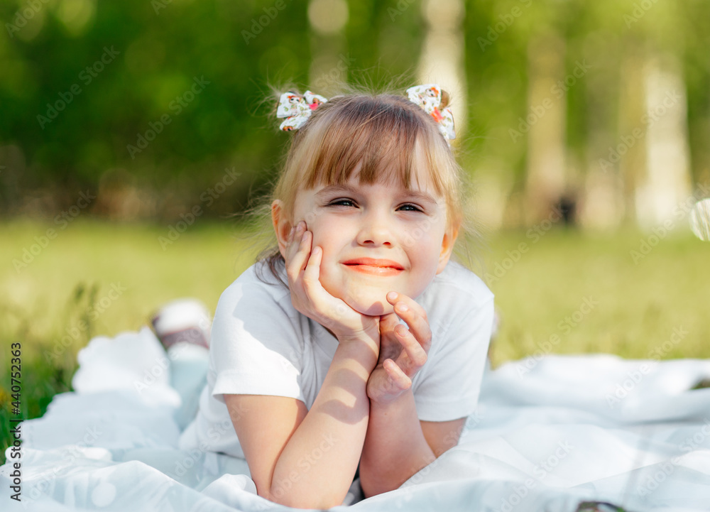 Happy little girl plays on the grass in the park in the summer Happy little girl plays on the grass in the park in the summer