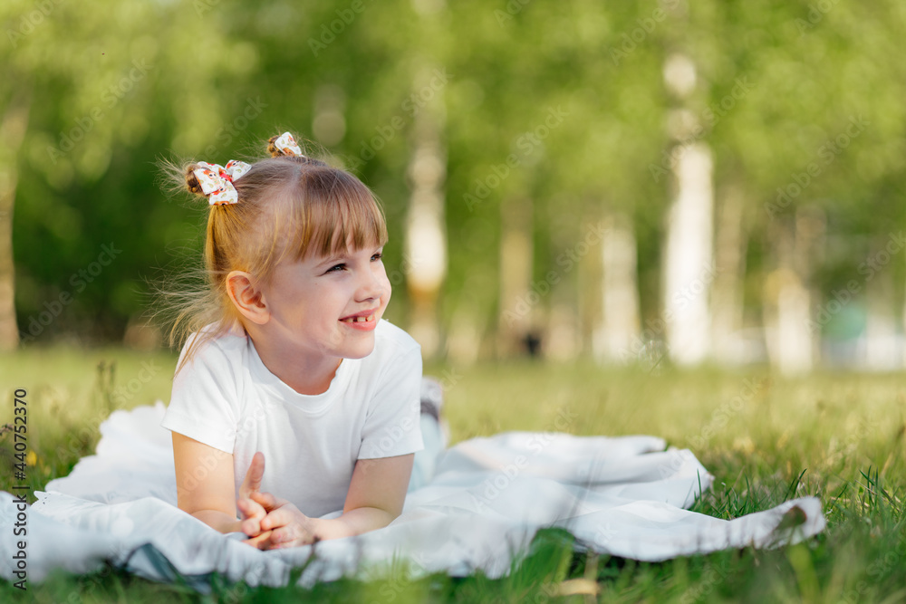 Happy little girl plays on the grass in the park in the summer Happy little girl plays on the grass in the park in the summer