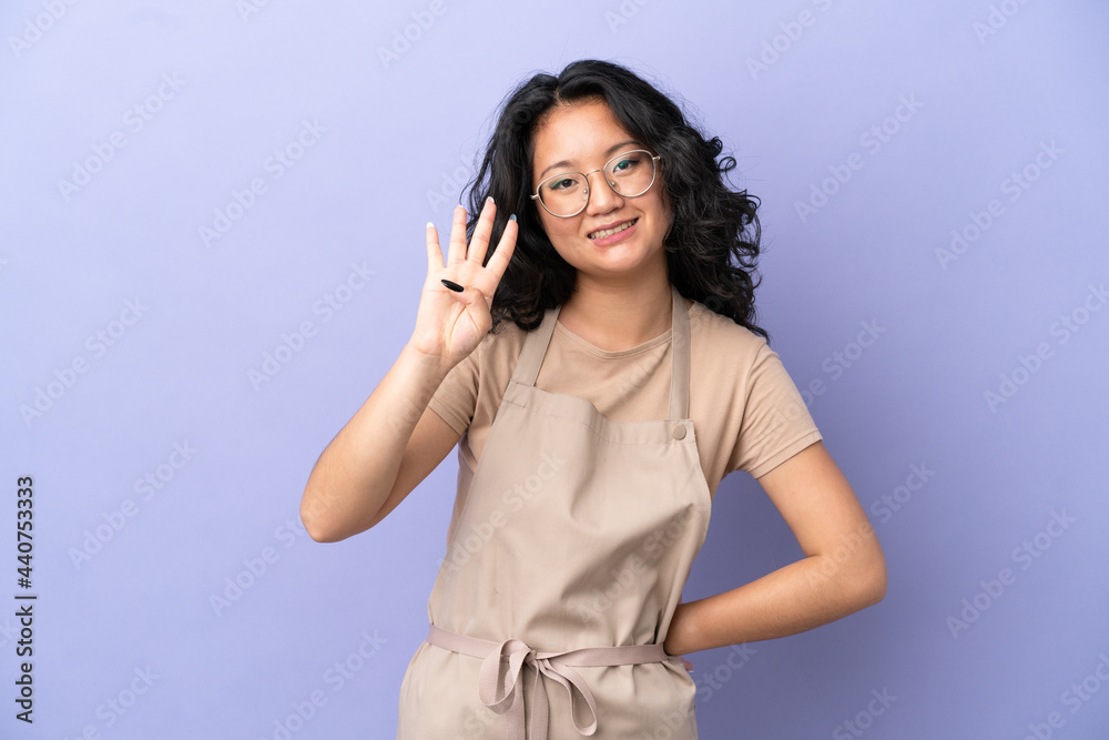 Restaurant asian waiter isolated on purple background happy and counting four with fingers Restaurant asian waiter isolated on purple background happy and counting four with fingers