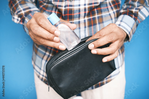 man hand putting hand sanitizer in small bag 