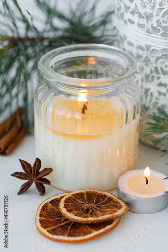 Rustic zero waste natural christmas decor. Candle in glass jar, spices, dry orange, green fir tree banches. Decoration for holiday dinner table. Happy new year. Holiday atmospere, festive mood