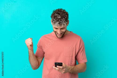 Foto Young handsome caucasian man isolated on blue background surprised and sending a