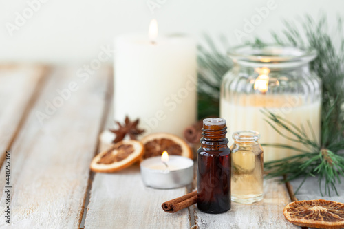Assortment of natural christmas essential oils in small bottles. Candles, branches of fir tree. Aromatherapy, cozy home atmosphere, holiday festive mood. Close up macro, wooden background. Zero waste photo