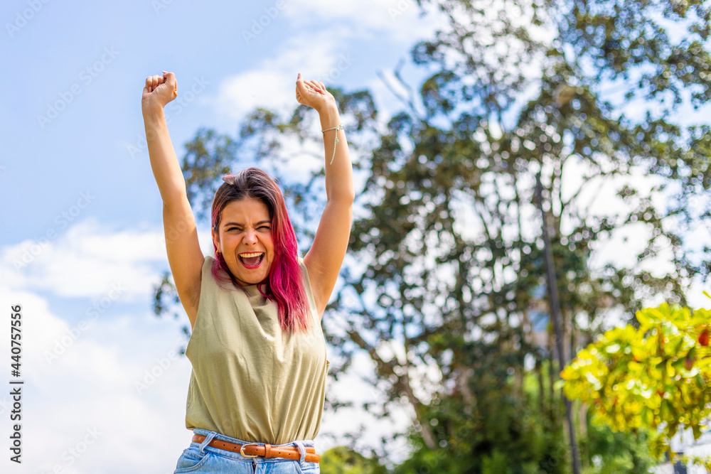 young latin woman celebrating with her hands up in the air