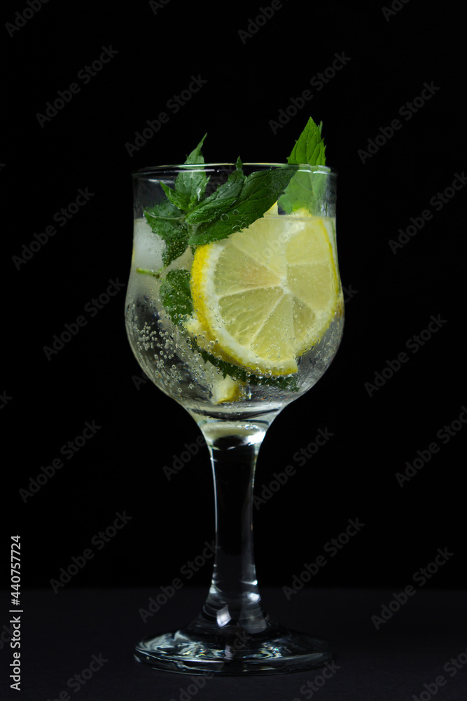 Refreshing cocktail with ice, lemon and mint on a black background. Non-alcoholic cocktail. Refreshing cocktail with ice, lemon and mint on a black background. Non-alcoholic cocktail.