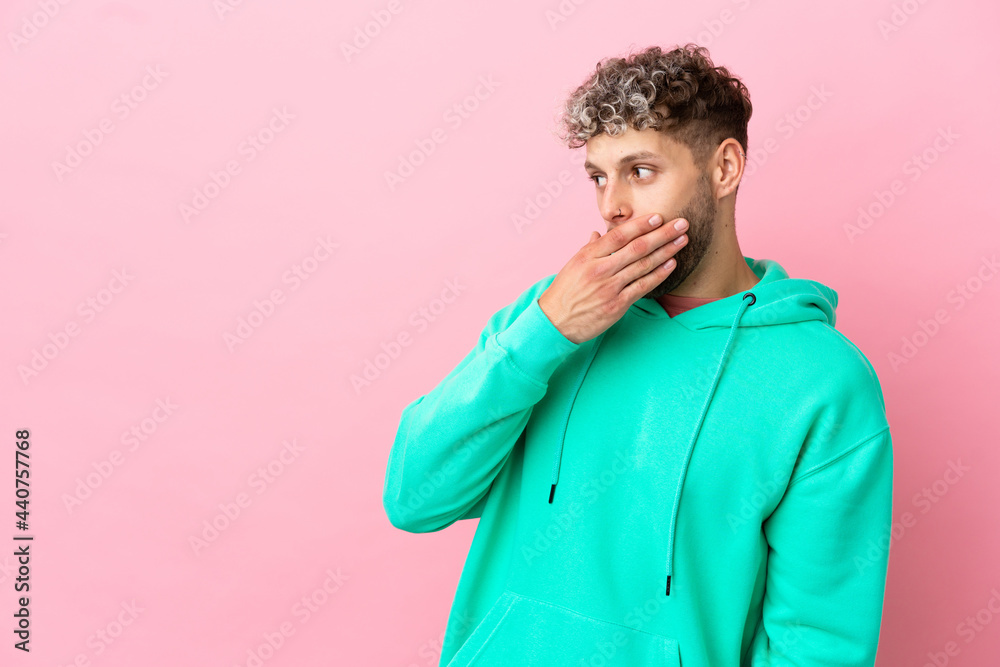 Young handsome caucasian man isolated on pink background doing surprise gesture while looking to the side Young handsome caucasian man isolated on pink background doing surprise gesture while looking to the side