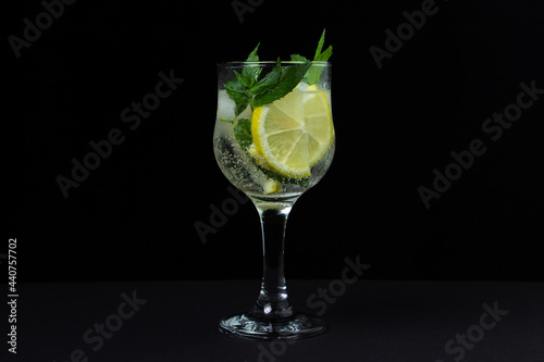 Refreshing cocktail with ice, lemon and mint on a black background. Non-alcoholic cocktail.