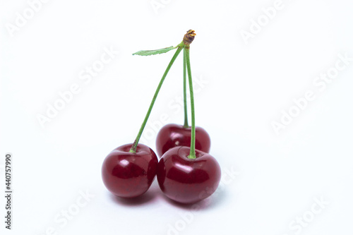 Ripe cherries on a white background. Three cherries on one branch. Delicious fruit