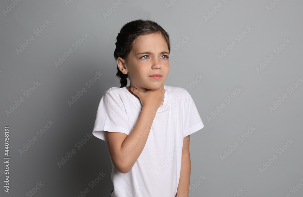 Little girl suffering from sore throat on grey background Little girl suffering from sore throat on grey background