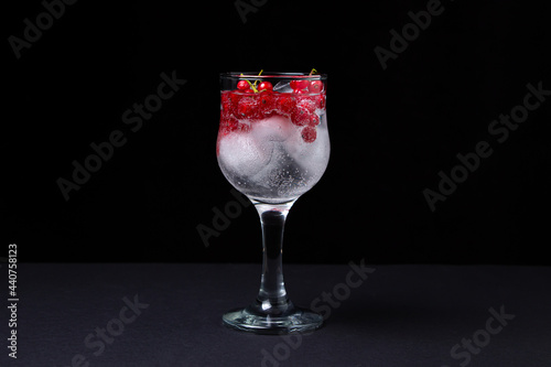 Refreshing cocktail with ice and red currants on a black background. Non-alcoholic cocktail.