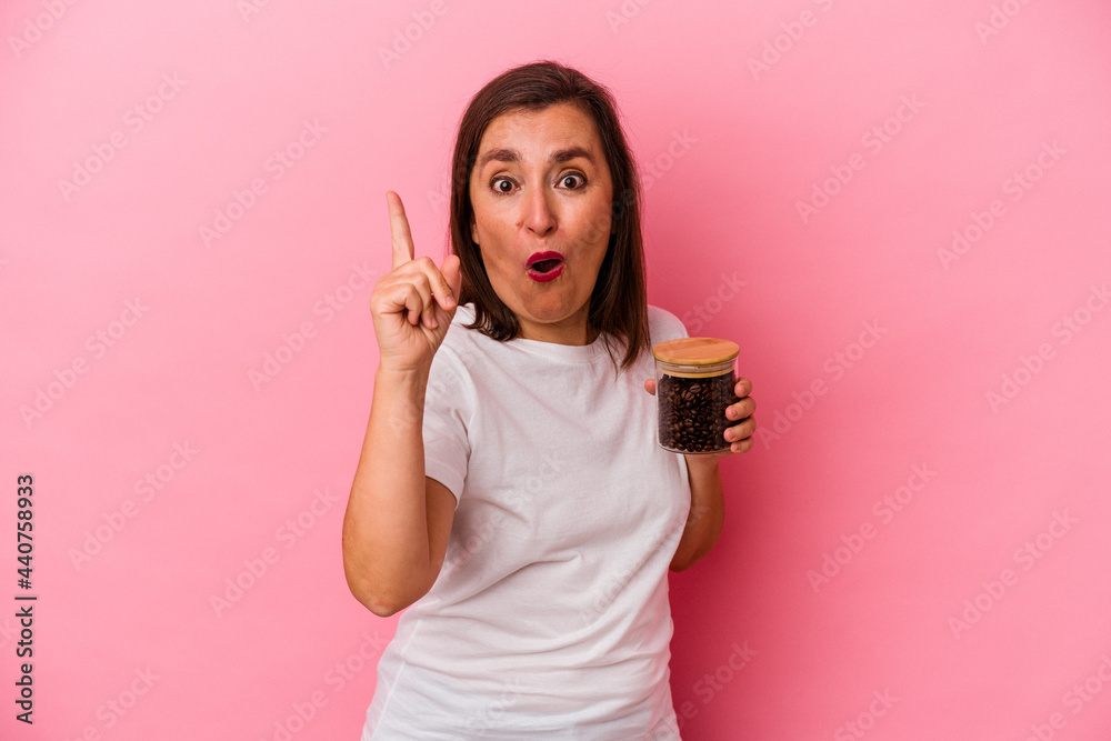 Middle age caucasian woman holding a coffee jar isolated on pink background having an idea, inspiration concept. Middle age caucasian woman holding a coffee jar isolated on pink background having an idea, inspiration concept.