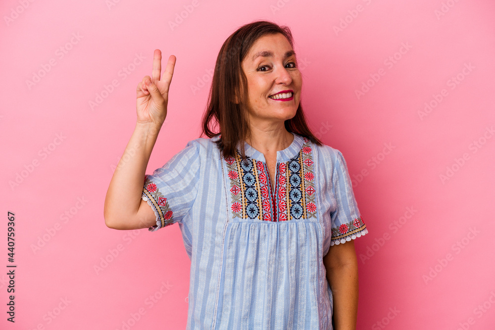 Middle age caucasian woman isolated on pink background showing victory sign and smiling broadly. Middle age caucasian woman isolated on pink background showing victory sign and smiling broadly.