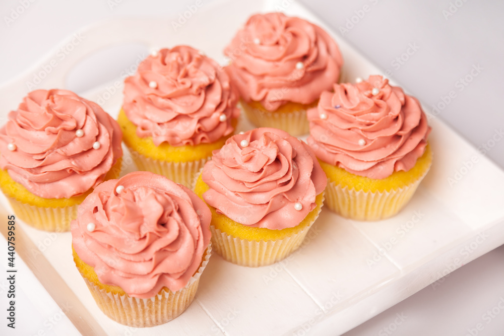 Fresh and delicious cupcakes with yogurt cream. Cakes with cream on table. Muffin with cream. Ready-made pastry, dessert for serving. Indoor studio shot isolated on pink background.