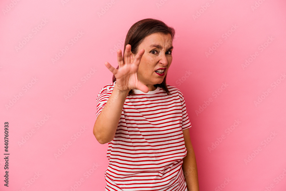 Middle age caucasian woman isolated on pink background showing claws imitating a cat, aggressive gesture. Middle age caucasian woman isolated on pink background showing claws imitating a cat, aggressive gesture.