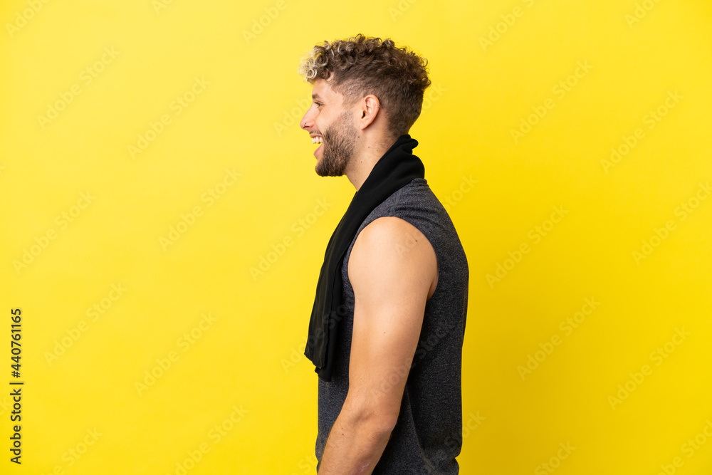 Sport caucasian man isolated on yellow background laughing in lateral position Sport caucasian man isolated on yellow background laughing in lateral position