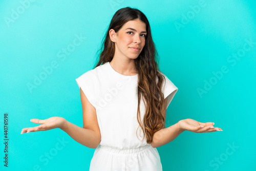 Young caucasian woman isolated on blue background having doubts