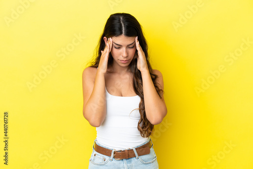 Young caucasian woman isolated on yellow background with headache