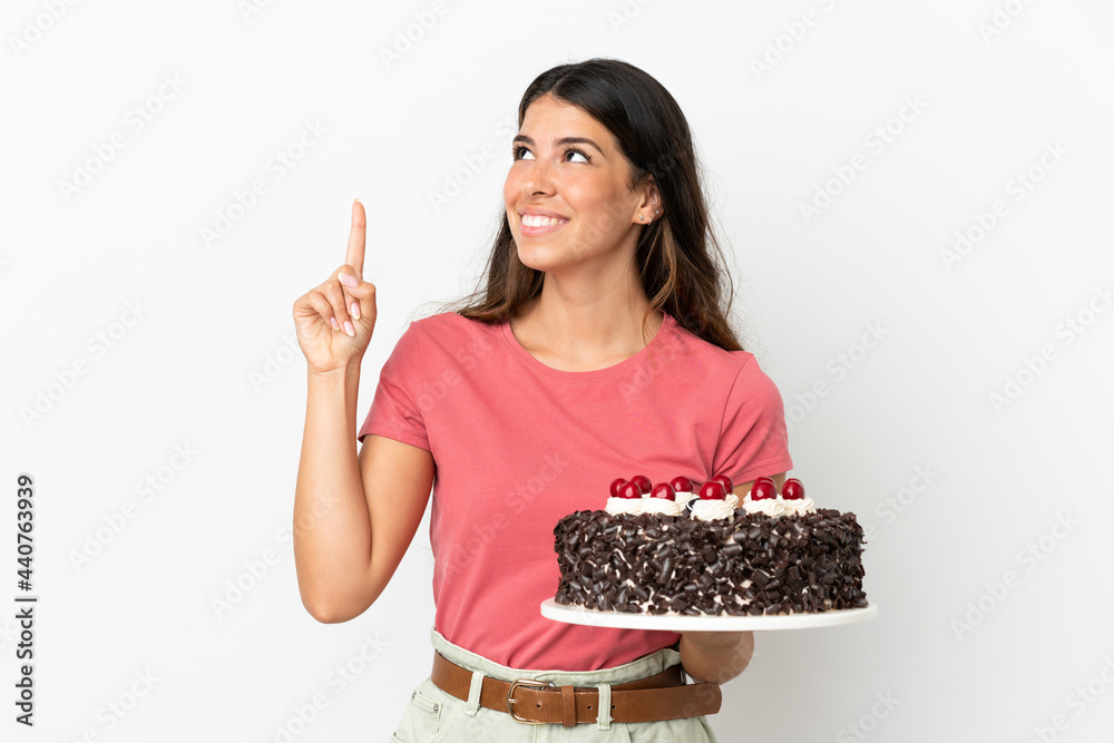 Young caucasian woman holding birthday cake isolated on white background pointing up a great idea Young caucasian woman holding birthday cake isolated on white background pointing up a great idea