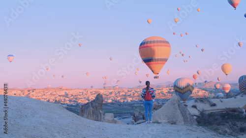 Female traveler with backpack looking to the air baloons. sporty girl and a lot of hot air balloons. The feeling of complete freedom, achievement, achievement, happiness