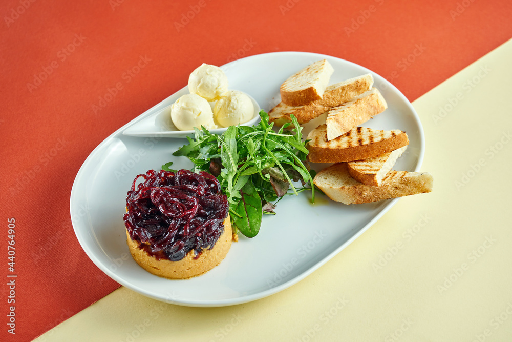 Turkey liver pate with onion confit, curtons in a white plate on bright colored backgrounds