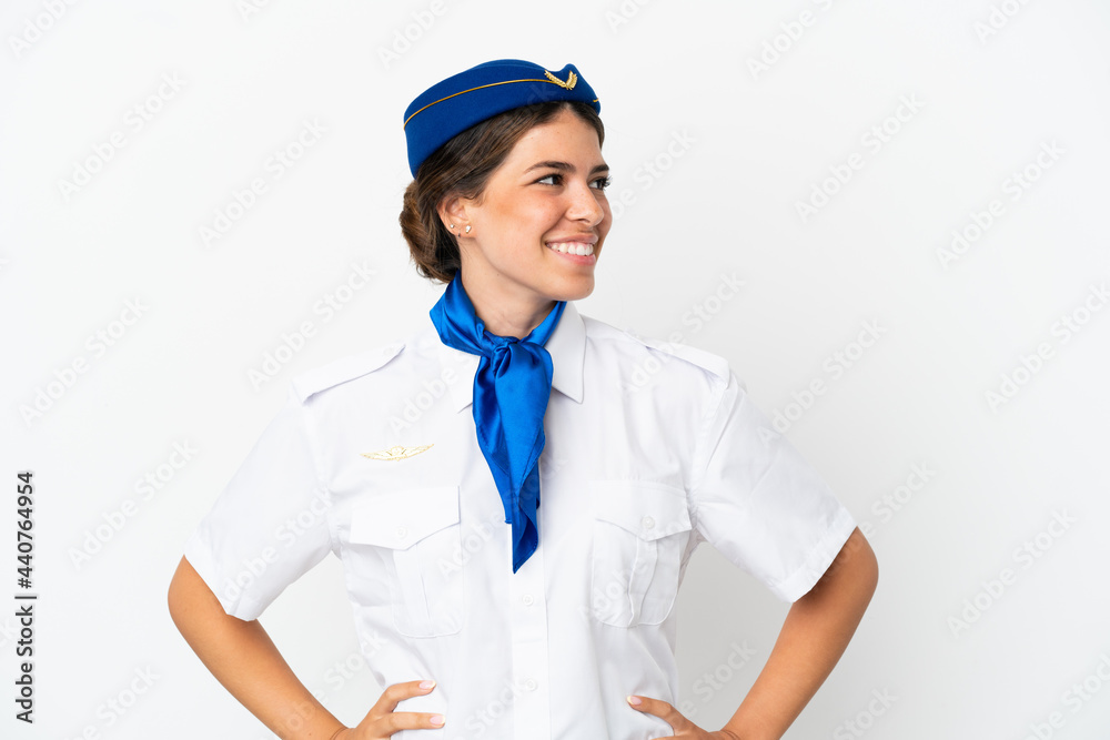 Airplane stewardess caucasian woman isolated on white background posing with arms at hip and smiling Airplane stewardess caucasian woman isolated on white background posing with arms at hip and smiling