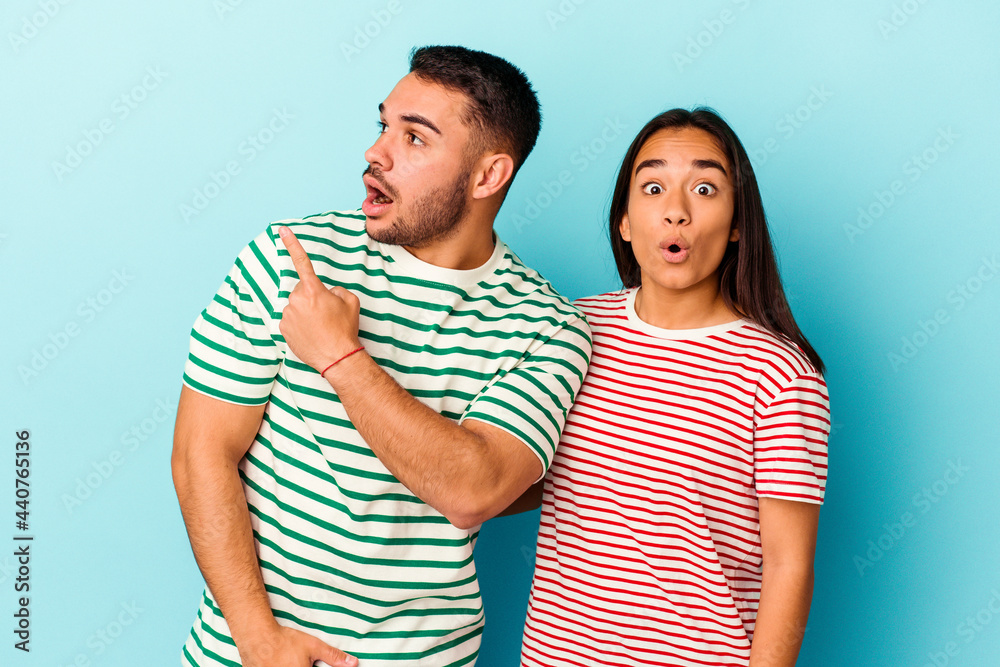 Young mixed race couple isolated on blue background pointing to the side Young mixed race couple isolated on blue background pointing to the side