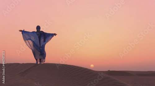 Photography Portrait of beautiful Arab woman weared in blue traditional dress in the desert during sunset